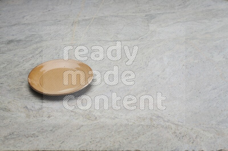 A beige pottery plate on grey marble background