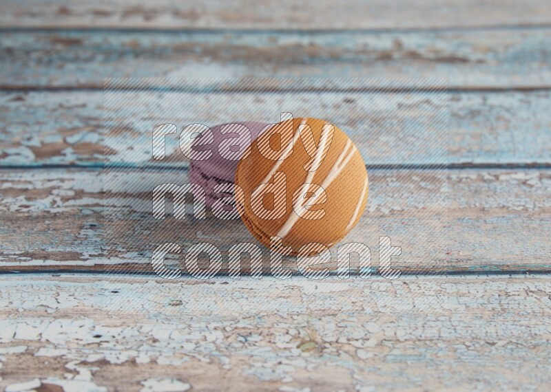 45º Shot of of two assorted Brown Irish Cream, and Purple Blueberry macarons  on light blue background