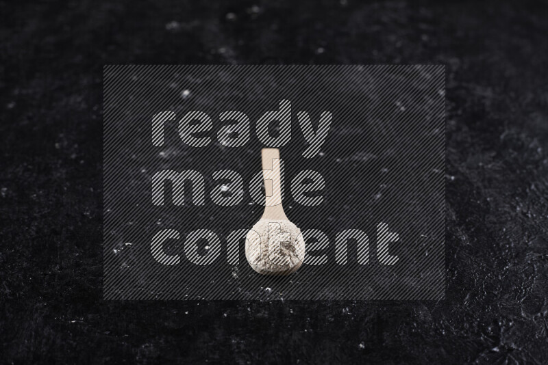 ملعقة خشبية ممتلئة ببودرة البصل علي خلفية سوداء