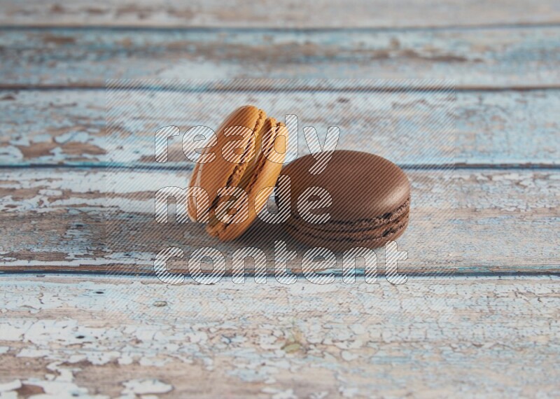 45º Shot of of two assorted Brown Irish Cream, and Brown Dark Chocolate macarons on light blue background