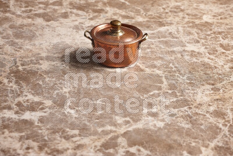 A small copper pot on beige marble background