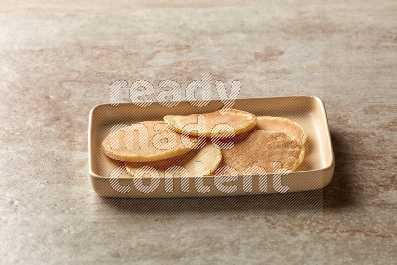 Five stacked plain mini pancakes in a rectangular plate on beige background