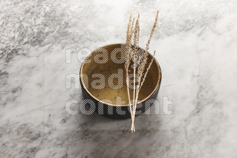 Wheat stalks on multicolored pottery oven plate on grey marble background