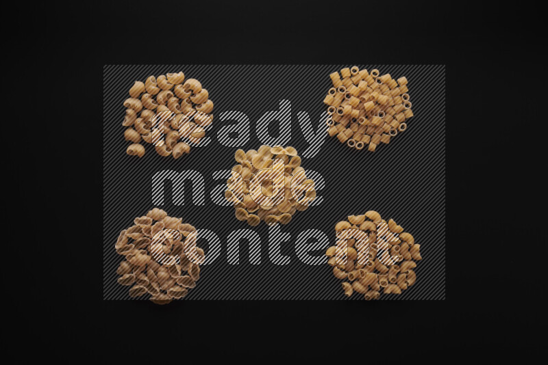 Different pasta types in bunches on black background