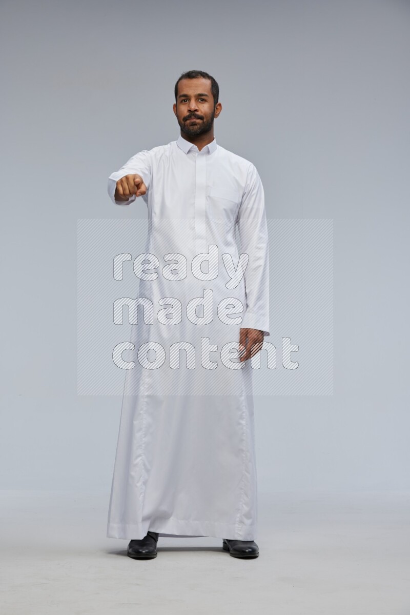 Saudi man Wearing Thob standing interacting with the camera on Gray background