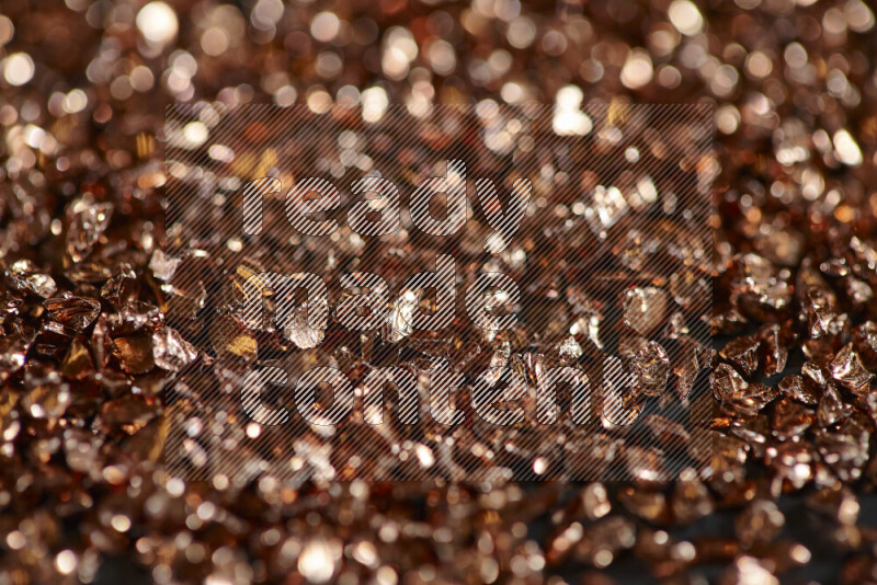 Bronze shimmering fragments of glass scattered on a black background