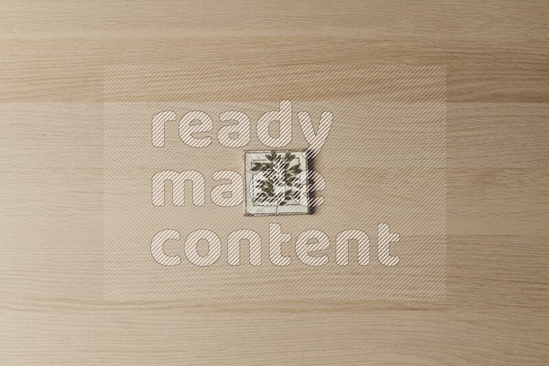 A decorative pottery coaster on light wooden background