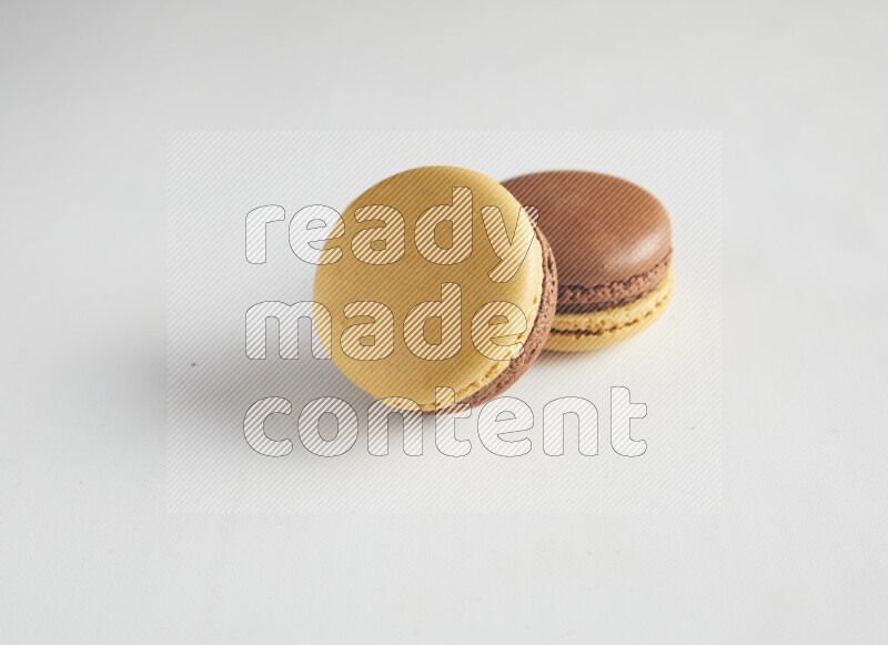 45º Shot of two Yellow and Brown Chai Latte macarons on white background