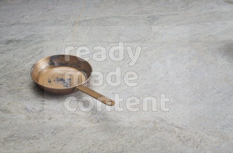 A small copper pan on grey marble background