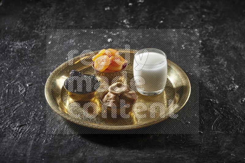 Dried fruits in metal bowls with sobya on a tray in dark setup