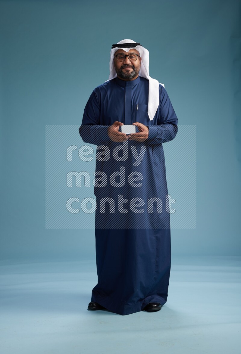Saudi Man with shimag Standing holding ATM on blue background