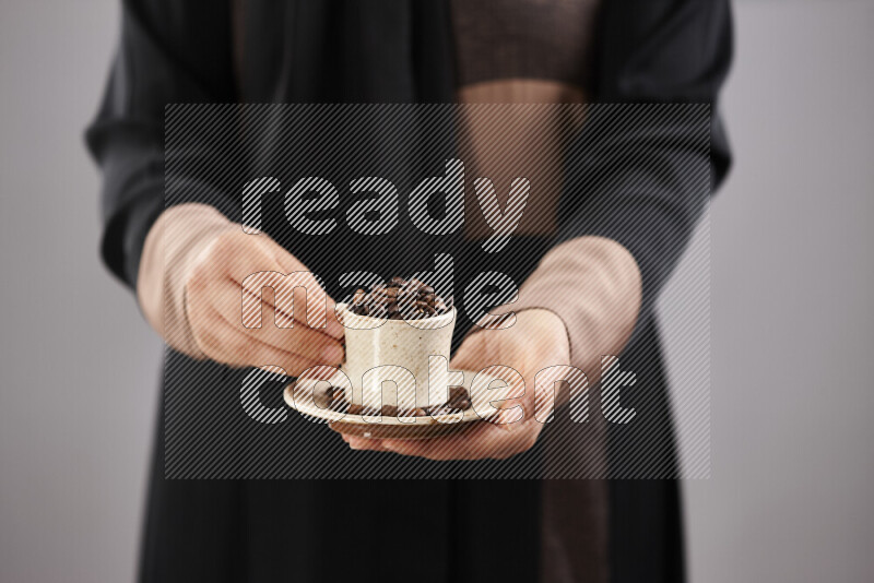 Woman in abaya holding different kinds of coffee beans in different positions