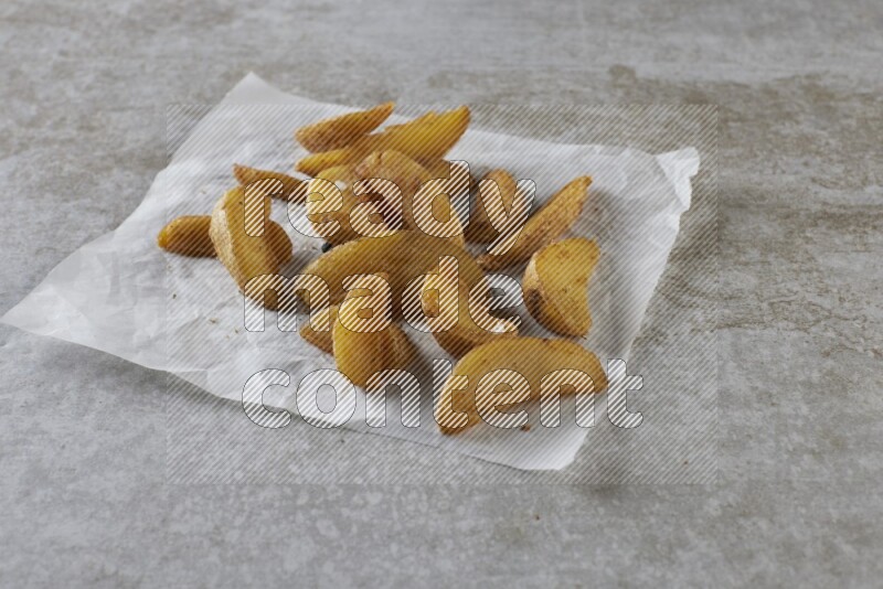 wedges potato on parchment paper on grey textured counter top