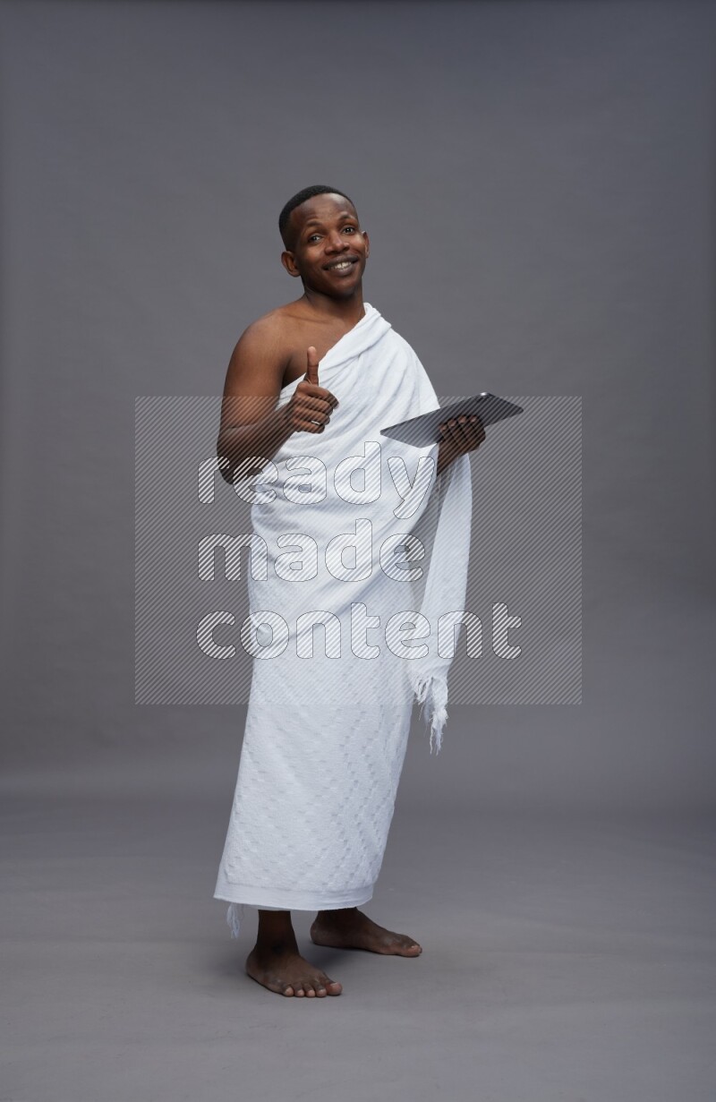 A man wearing Ehram Standing working on tablet on gray background