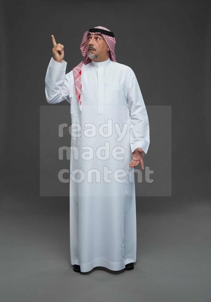 Saudi man with shomag Standing Interacting with the camera on gray background
