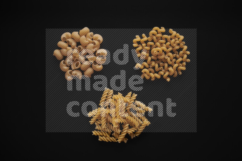 Different pasta types in bunches on black background