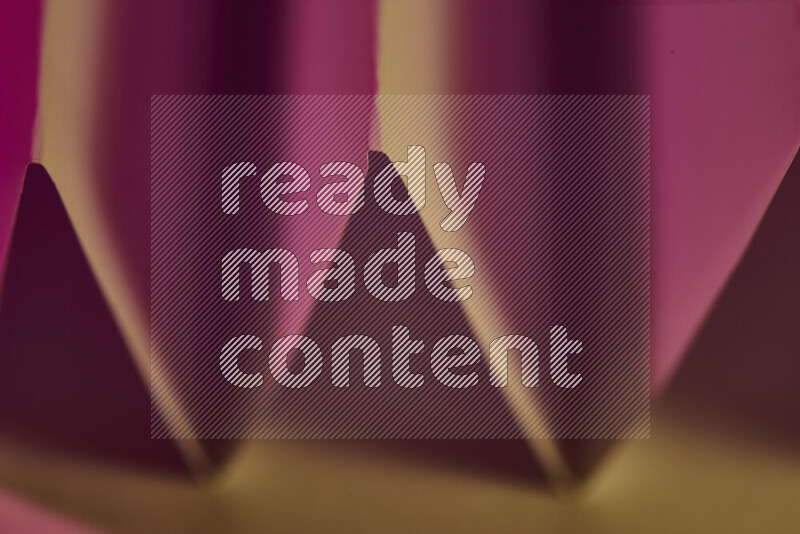 صورة مجردة مقربة تظهر طيات ورقية هندسية حادة بتدرجات اللون الوردي مع درجات لونية دافئة