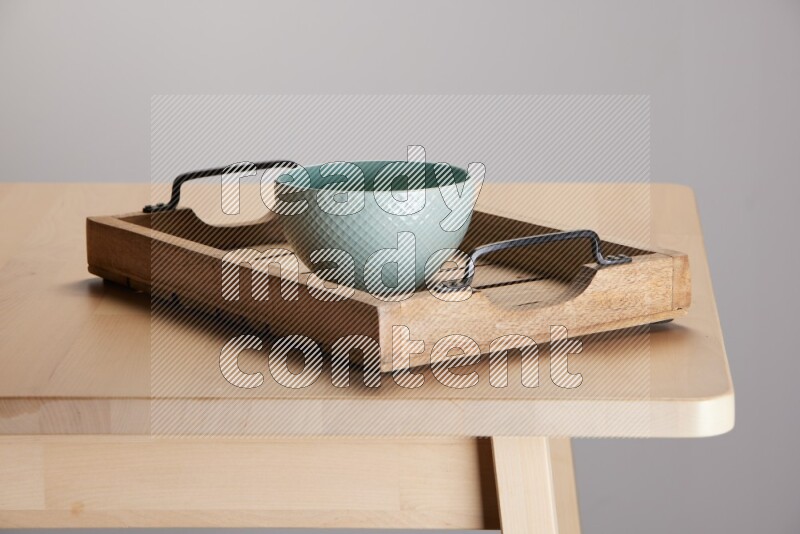 blue bowl on a light colored rectangular wooden tray with handles