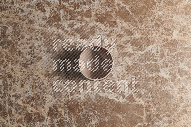A multicolored pottery bowl on beige marble background