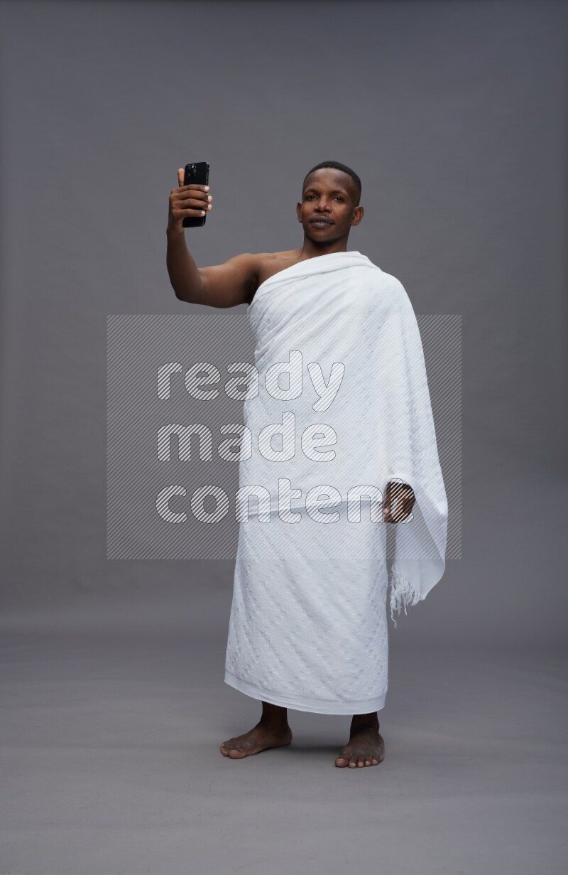 A man wearing Ehram Standing taking selfie on gray background