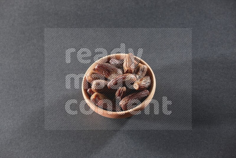A wooden bowl full of dried dates on a black background in different angles