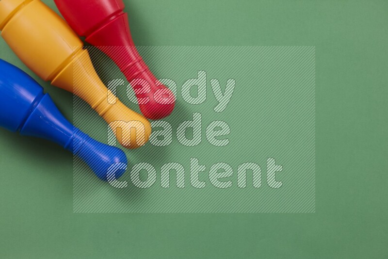 أوتاد البولينج البلاستيكية الملونة علي خلفيات ملونة مختلفة (ألعاب أطفال)