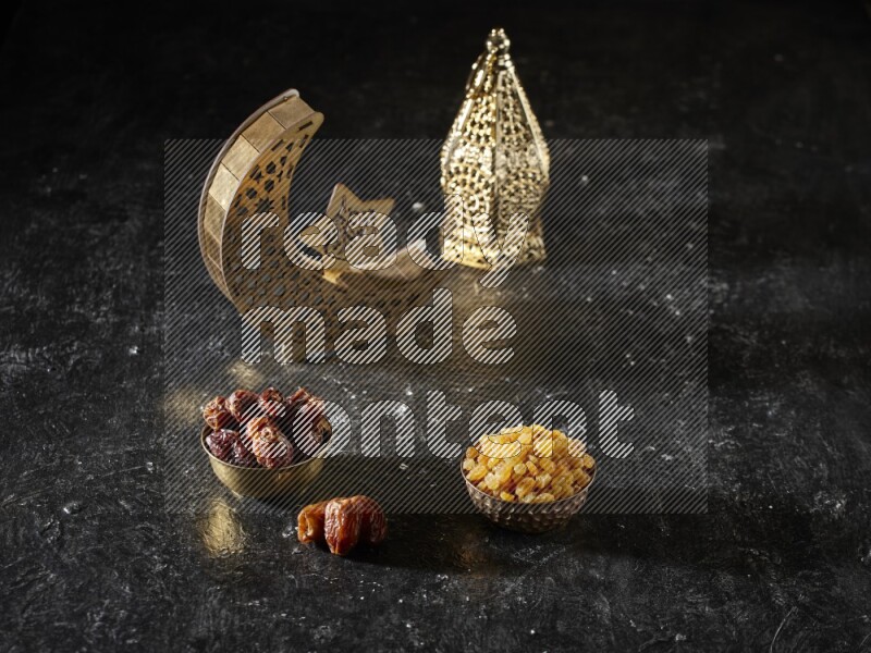 Dates in a metal bowl with raisins beside golden lanterns in a dark setup