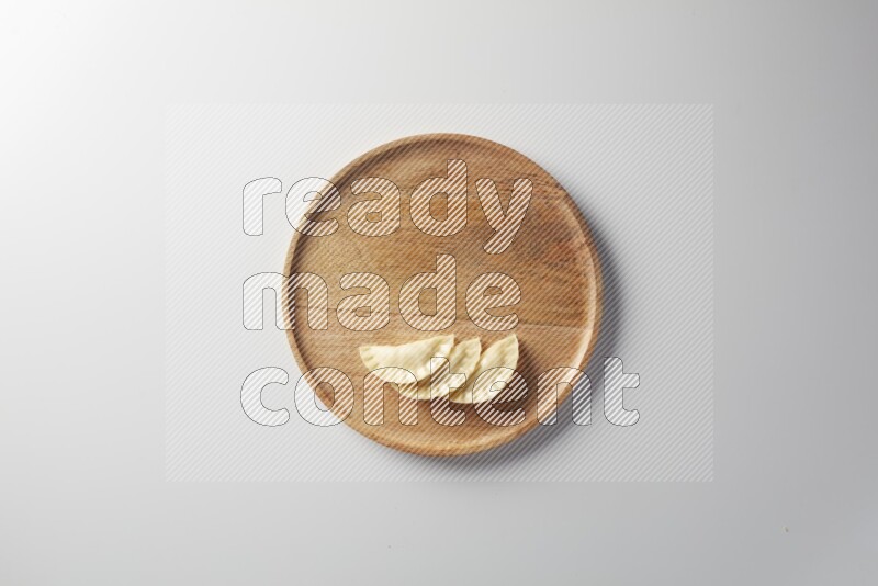 Three Sambosas on a wooden round plate on a white background