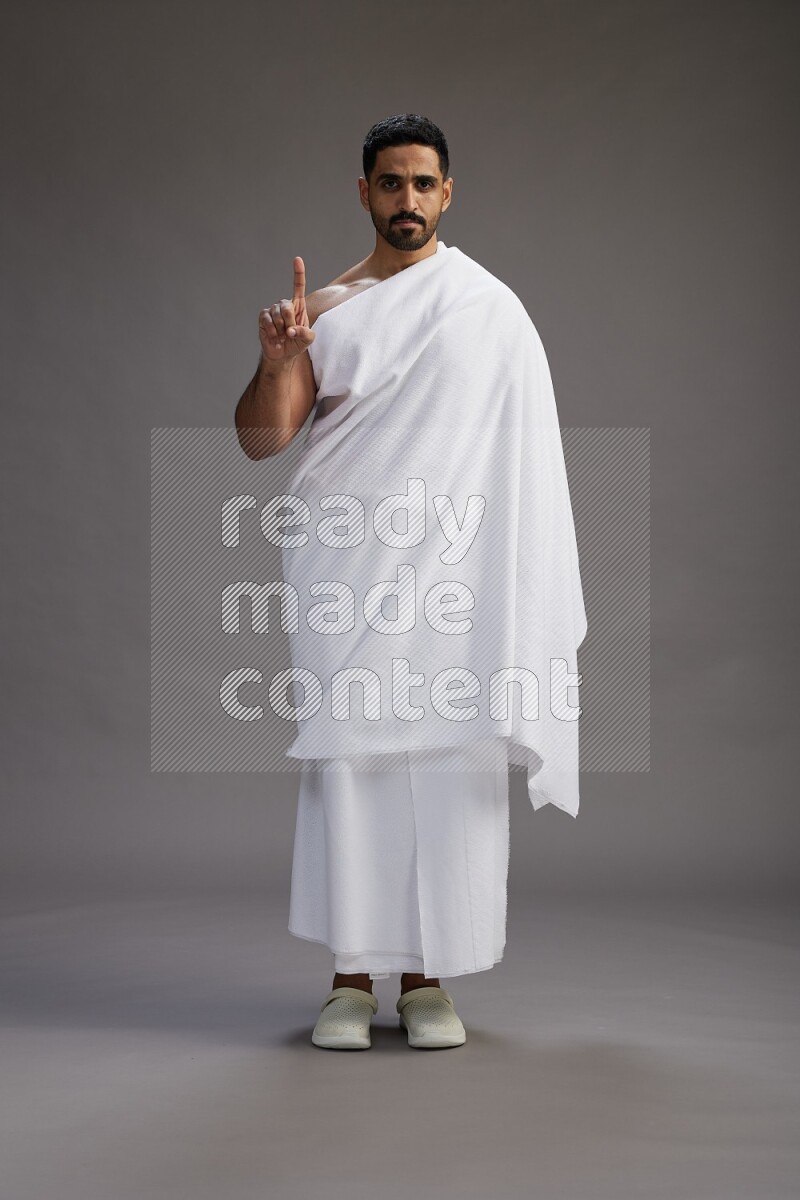 A man wearing Ehram Standing Interacting with the camera on gray background