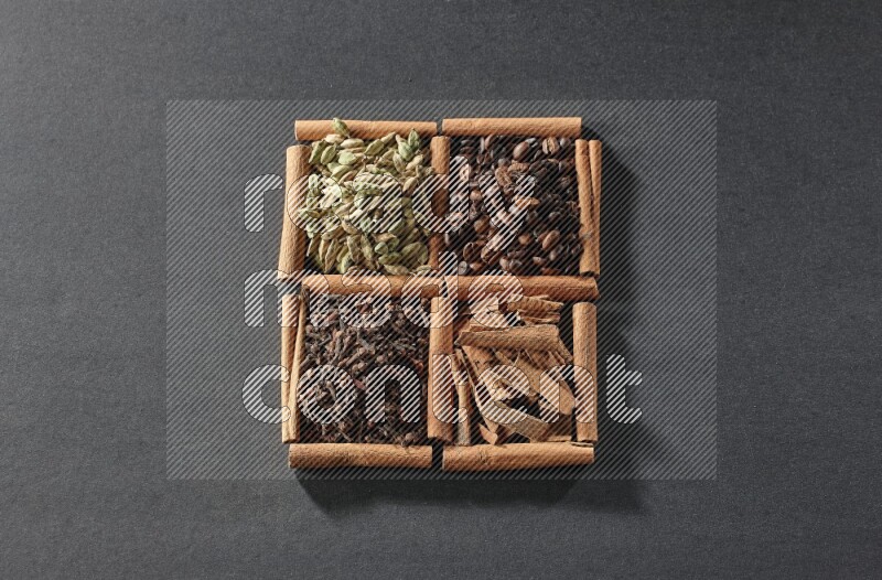 4 squares of cinnamon sticks full of coffee beans, cinnamon, cloves and cardamom on black flooring