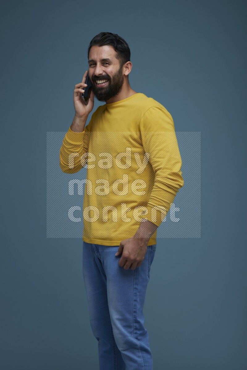 A man having a calling in a blue background wearing a yellow shirt