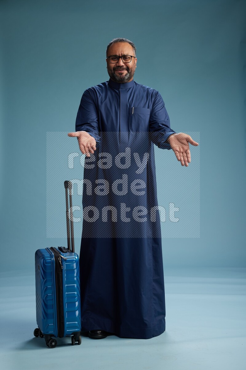 Saudi Man without shimag Standing pulling travel bag on blue background