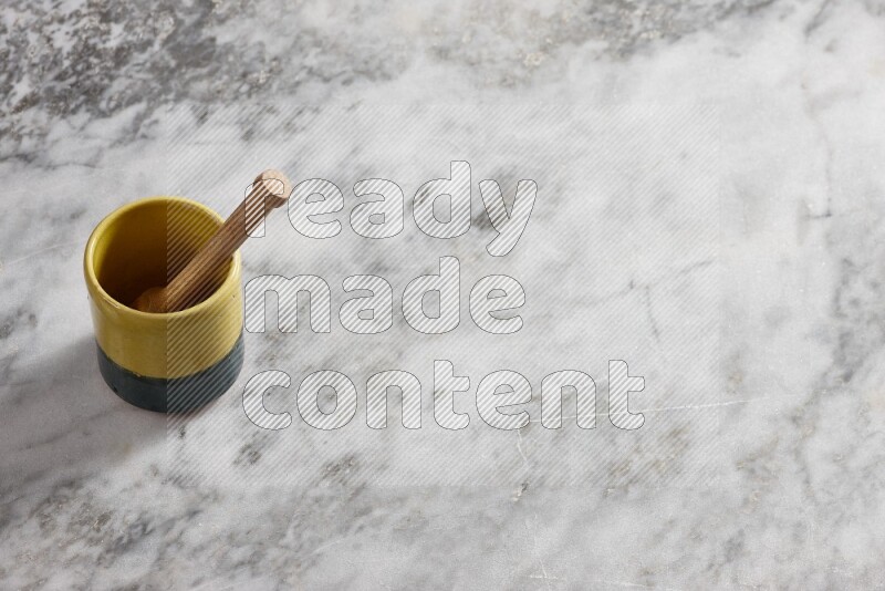 Multicolored pottery cup with wooden honey dipper in it on grey marble background