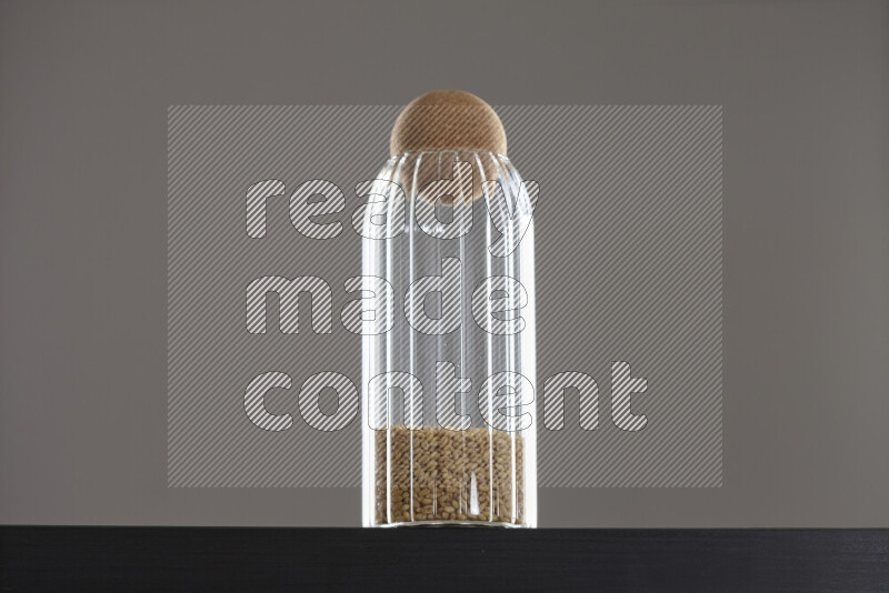 Hulled wheat in a glass jar on black background