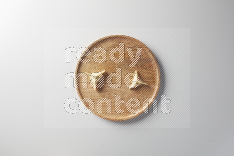 Two Sambosas on a wooden round plate on a white background
