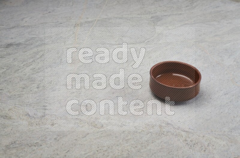 A brown pottery bowl on grey marble background