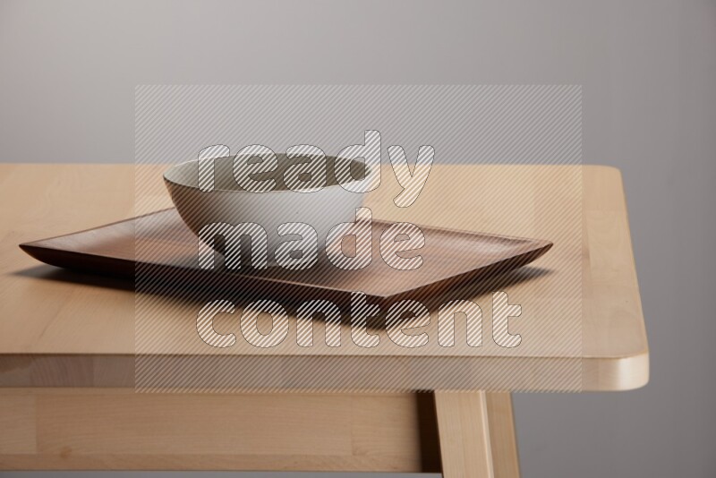 off white bowl with islamic pattern placed on a rectangular wooden tray on the edge of wooden table