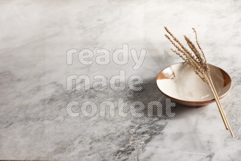 Wheat stalks on multicolored pottery plate on grey marble background