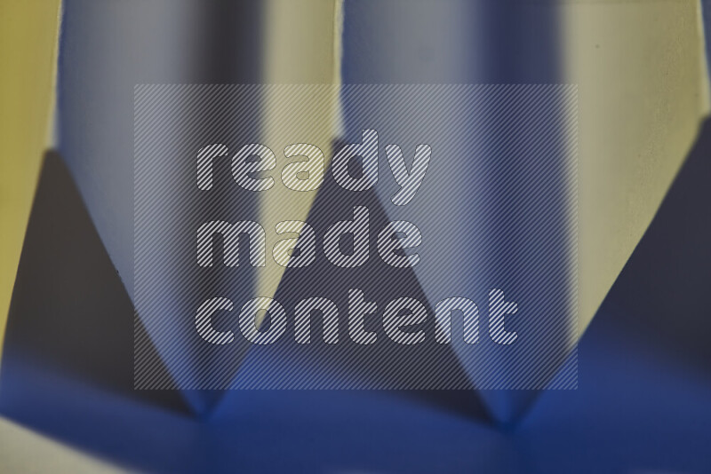 A close-up abstract image showing sharp geometric paper folds in blue gradients and warm tones