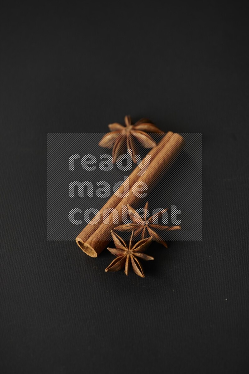 Star Anise herb and a cinnamon stick on a black background