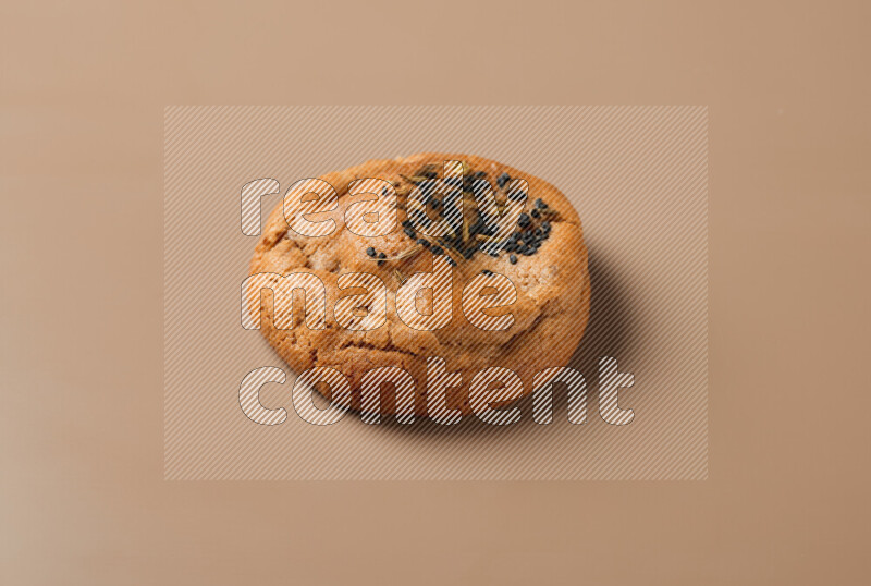 a whole Hasawi cookie with grains on a brown background