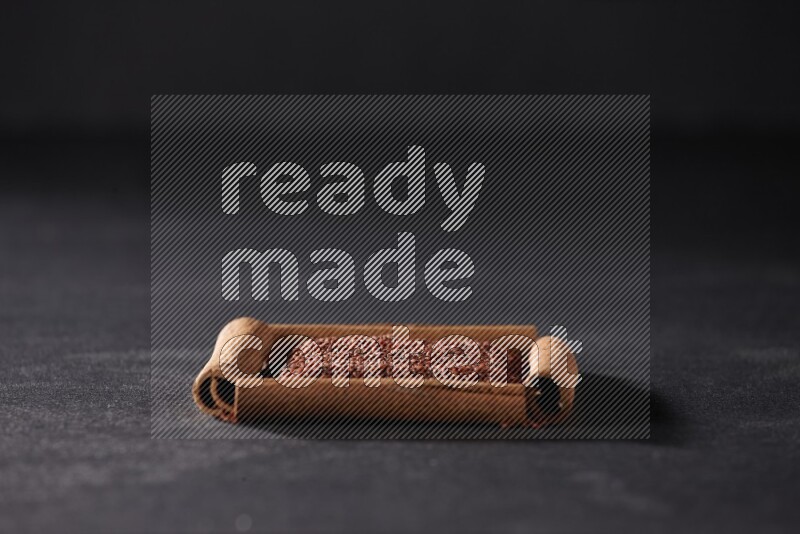 A single square of cinnamon sticks full of garden cress on black flooring