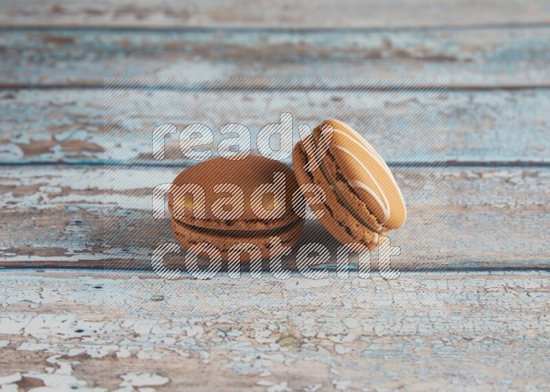 45º Shot of of two assorted Brown Irish Cream, and Brown Coffee macarons on light blue background