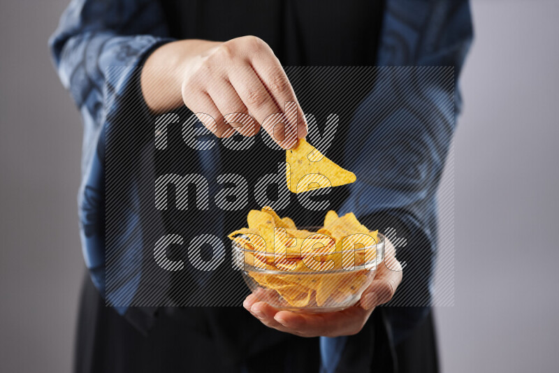 Woman in abaya holding different kinds of snacks in different positions