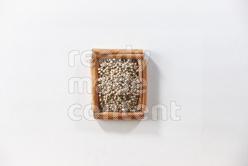 A single square of cinnamon sticks full of white pepper on white flooring