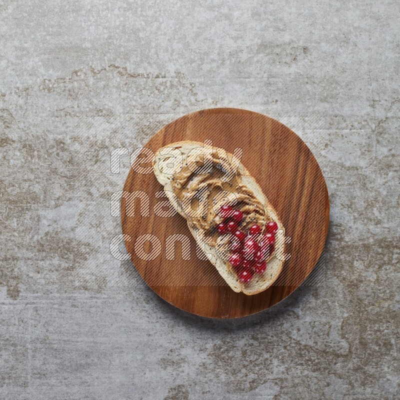 open faced peanut butter sandwich with cranberries and chia seeds grey textured background