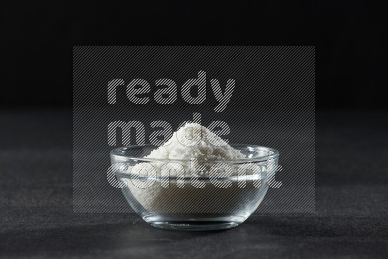 A glass bowl full of desiccated coconut on a black background in different angles