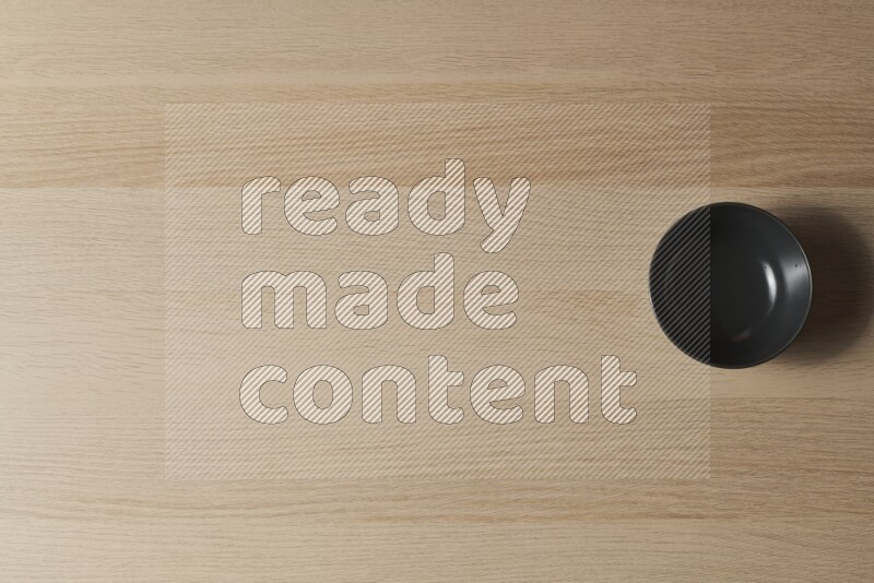 A black ceramic bowl on light wooden background