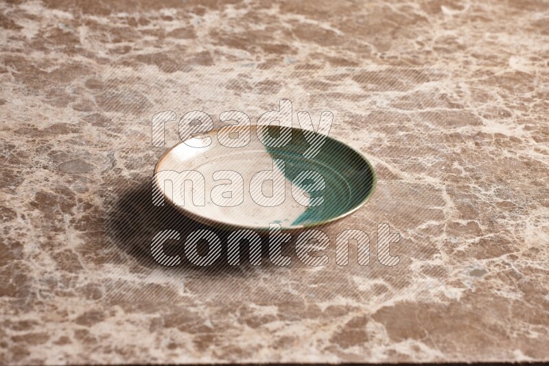 A multicolored pottery plate on beige marble background