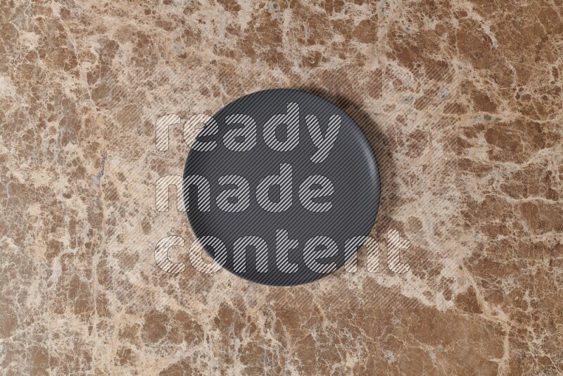 Top View Shot Of A Black Ceramic Circular Plate On beige Marble Flooring